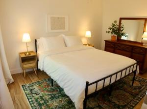 a bedroom with a large white bed and a mirror at The Gentry Hideaway, A Private Mayberry Retreat in Mount Airy
