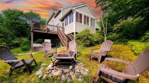 a group of chairs around a fire pit in front of a house at The Nest at Pinecrest by AvantStay Spacious Deck Game Room Fire Pit in Pocono Pines