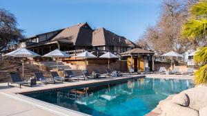 a pool with chairs and umbrellas in front of a building at Cathedral by AvantStay Charming Secluded Estate w Sauna Pool Table Views of the Rolling Hills in Paso Robles