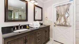 a bathroom with a sink and a mirror and a door at Dawn and Dusk by AvantStay Modern Cabin in Great Location w Home Theatre in Big Bear Lake +58 photos