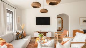 a living room with a couch and a tv at Flora by AvantStay Modern Private Desert Oasis on Large Grounds w Pool Bocce Ball in Yucca Valley