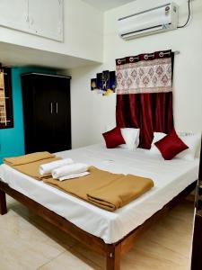 a bedroom with a large bed with white sheets and red pillows at Kumbha Nivas in Kumbakonam