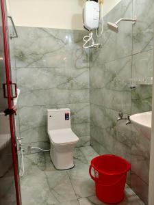 a bathroom with a toilet and a sink and a red bucket at Kumbha Nivas in Kumbakonam +6 photos