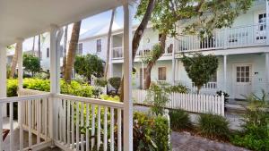 a white house with a white fence and trees at Beach House Condo by AvantStay Communal Pool Gated Community Great Location Week Long Stays in Key West