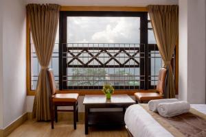 a bedroom with a window and a bed and a table at Gangtok Central Rooms in Gangtok +63 photos