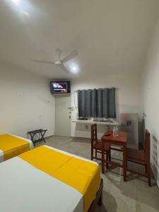 a room with two beds and a table and a tv at Hotel AF 4 in Tizimín