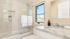 a white bathroom with a tub and a sink and a shower at Sea Crown by AvantStay 5mins from the Beach w Multiple Terraces PermitSLP13639 in Newport Beach +38 photos