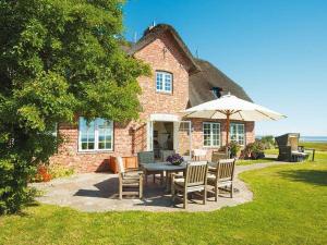 une maison en briques avec une table, des chaises et un parasol dans l'établissement Pueckdeel, à Kampen