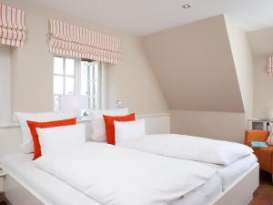 two beds in a room with white and orange pillows at Vis-a-Vis in Kampen