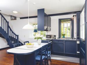 a kitchen with blue cabinets and a table with chairs at Schroeders-Haus-Sued in Kampen