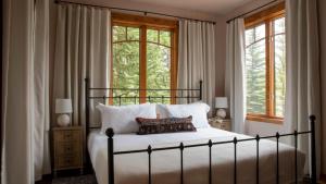 Un dormitorio con una cama con sábanas blancas y ventanas. en Zendo by AvantStay Serene Mountain Abode w Hot Tub Views, en Breckenridge