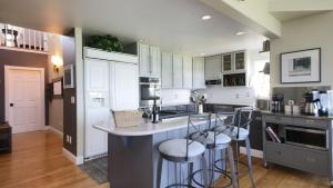 a kitchen with white cabinets and a island with bar stools at Fairway Harbor View by AvantStay Outdoor Oasis in Freeland
