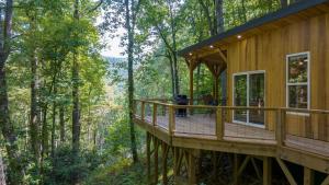 une maison dans les bois entourée d'une terrasse dans l'établissement Artist’s Palette by AvantStay Colorful Retreat, à Fairview