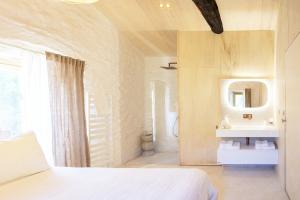 a bedroom with a white bed and a mirror at Historic Chestnut Kiln With Pool In The Cévennes in Les Plantiers +20 photos