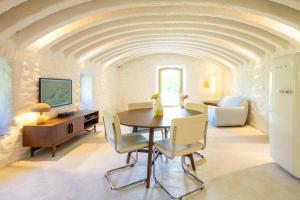 a living room with a dining room table and chairs at Historic Chestnut Kiln With Pool In The Cévennes in Les Plantiers