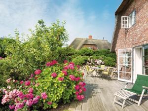 un patio con fiori rosa, tavolo e sedie di Haus-zum-Leuchtturm a Kampen Altre 8 foto