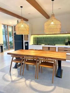 ein großer Holztisch in einer Küche mit zwei Pendelleuchten in der Unterkunft Luxury 3 bedroom villa Kupu Kupu in Nusa Lembongan