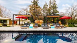 a swimming pool with chairs and umbrellas next to a swimming pool at Marquee By AvantStay Modern Stylish Estate w Pool Entertainers Courtyard in Boyes Hot Springs