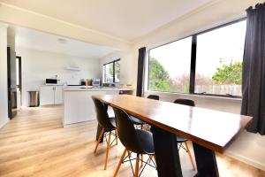 a kitchen and dining room with a wooden table and chairs at Tamarillo Bach - Coastal Comfort in Coopers Beach