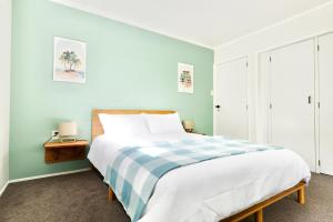 a bedroom with a large bed with a blue wall at Tamarillo Bach - Coastal Comfort in Coopers Beach