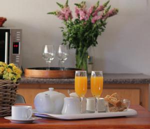 a table with two glasses of orange juice and a tea set at The Lantern Guesthouse in Bloemfontein
