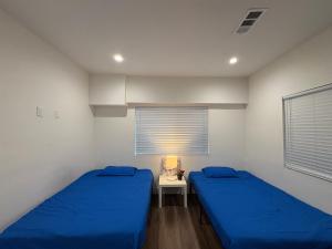 a bedroom with two beds and a table with a lamp at Blue Central Stay Near USC, BMO Stadium & Downtown LA in Los Angeles