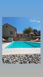 a swimming pool with rocks next to a house at La Caballeriza Hostel in Tanti Nuevo