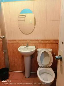 a bathroom with a toilet and a sink and a mirror at Wjv Inn Tabunok ll in Talisay