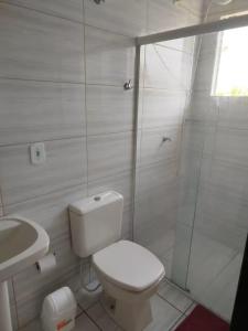a white bathroom with a toilet and a shower at Casa com piscina proximo da praia in Itapoa