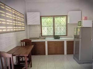 a kitchen with a wooden table and a refrigerator at Ban Elephant Blanc Bungalow in Kata Beach