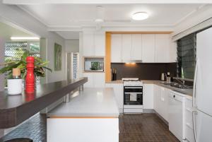 a kitchen with white cabinets and a black counter top at Island Holiday Memories in Nelly Bay in Nelly Bay