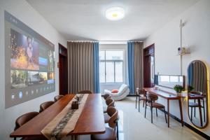 sala de estar con TV grande, mesa y sillas en Qianxun Jushe B&B, en Kaifeng