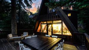 a house with a wooden table and chairs on a deck at Horizon by AvantStay Stunning A-frame Cabin w Hot Tub Billiards Lake Views in Tahoe City