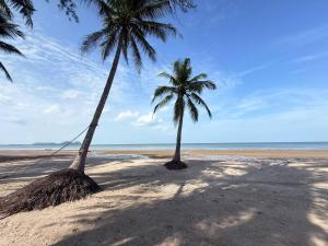two palm trees on a sandy beach with the ocean at BanrabianglayLangsuan room C in Ban Hin Sam Kon