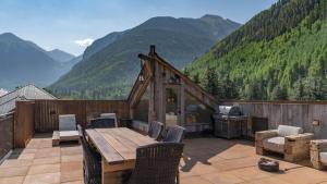 Una casa con una mesa y sillas en un balcón con montañas. en Ghostriders 11 by AvantStay Top Floor Condo w Large Patio Mountain Views, en Telluride