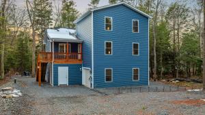 a blue house in the middle of a forest at Lakeview Sunset Heaven Waterfront Escape Private Dock Firepit Game Room New Construction in Blakeslee