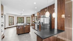 a large kitchen with wooden cabinets and a stainless steel refrigerator at Porch Paradise by AvantStay New Pool Firepit in Mooresville