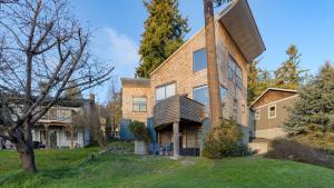 a house on a hill with a tree at Deck Views Fire Pit Pool 3 Mins to Beach Madrona Tree Retreat by AvantStay in Coupeville
