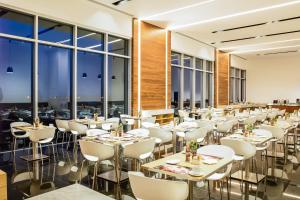 a restaurant with white tables and chairs and large windows at Fiesta Inn Pachuca Gran Patio in Pachuca de Soto