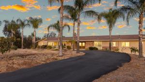 a house with palm trees in front of a driveway at Bordeaux by AvantStay Private Pool Hot Tub Game Room Near Temecula in Country Road Estates