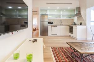 特拉維夫的住宿－Bright 2BD Apartment in the Heart of Tel Aviv by Sea N' Rent，一间大厨房,配有白色的橱柜和一张桌子
