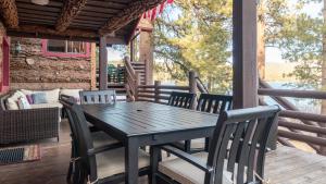 a wooden table and chairs on the porch of a house at Shoreline Lakehouse by AvantStay Majestic Lakefront Cabin w Hot Tub Fire Pit in Big Bear Lake +35 photos