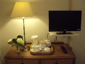 a table with a tv and a tray with cups and a lamp at Woodlands in Looe
