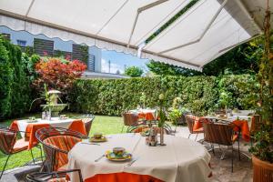 een patio met tafels en stoelen onder een witte parasol bij GORITSCHNIGGs Hotel - Self Check-In in Velden am Wörthersee
