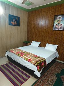 a bedroom with a large bed with a wooden wall at Radha Madhav in Vrindāvan +1 photo