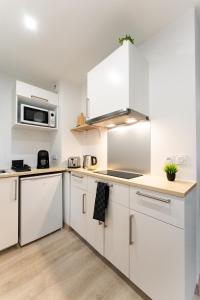 a white kitchen with white cabinets and appliances at Studio 27m² sur la Côte Pavée avec parking privé in Toulouse