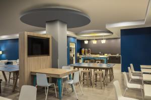 a dining room with tables and chairs and a tv at One Monterrey Tecnologico in Monterrey