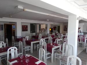 a dining room with white tables and white chairs at Hotel Los Juncos in Noja
