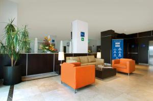 a lobby with two orange chairs and a couch at One Toluca Aeropuerto in Toluca