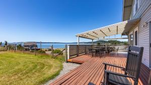 una terraza con mesa y bancos en una casa en Private Beach Access Water Views Sleeps 18 Historic 6BDR Farmhouse w Deck, en Clinton